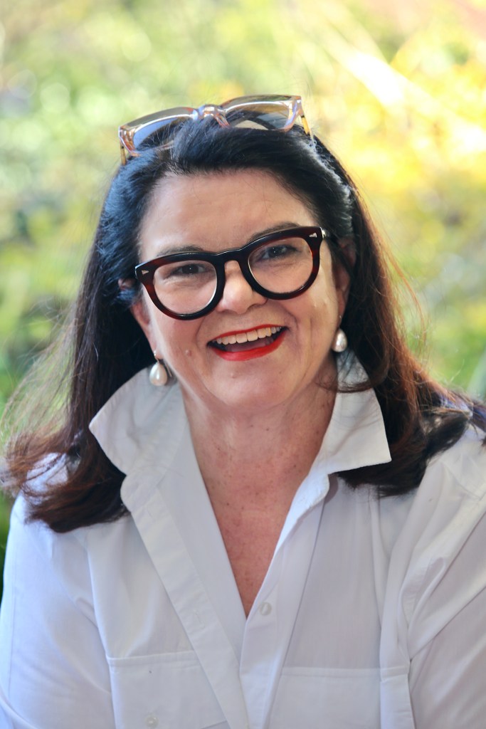 Jennifer Cowley wearing a white shirt and dark rimmed glasses with sun glasses on her head.